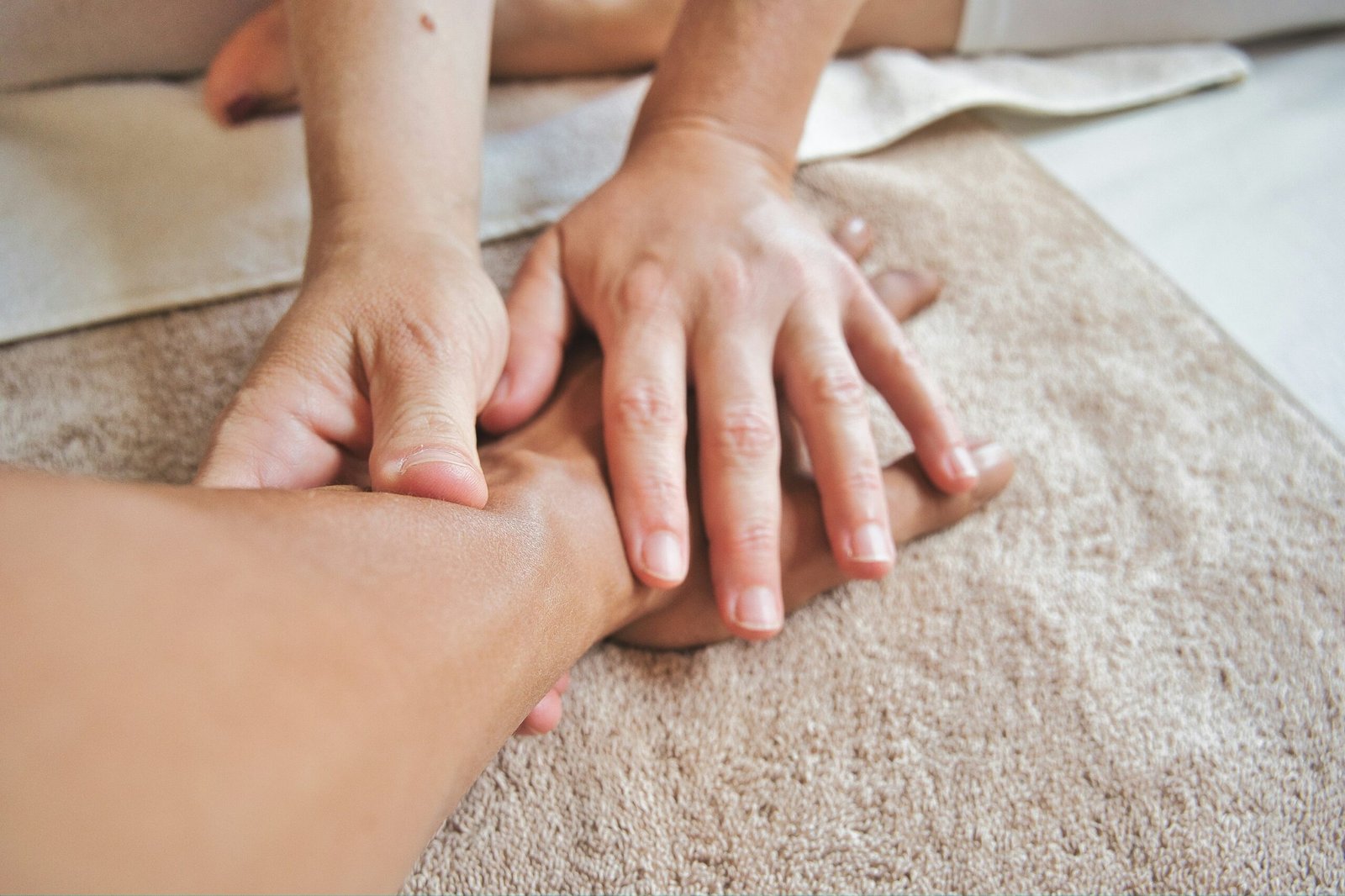 Mujer masajeando un brazo sobre una toalla beige